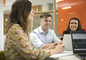 Three colleagues meeting and looking at laptops