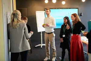 A workshop with attendees standing in front of a whiteboard