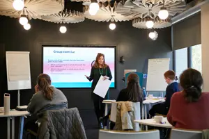 A workshop with electronic whiteboard and woman presenting