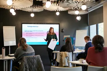 A workshop with electronic whiteboard and woman presenting