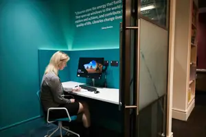 Woman sitting a a library desk in front of computer monitor