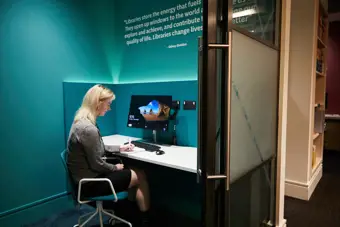 Woman sitting a a library desk in front of computer monitor