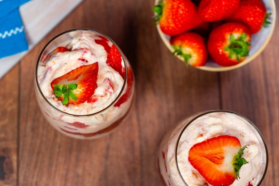 Strawberry eton mess dessert on a table beside a bowl of strawberries.