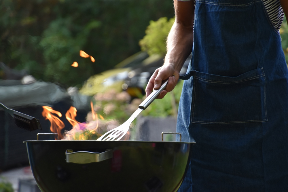 Man cooking on a BBQ in summer with apron on