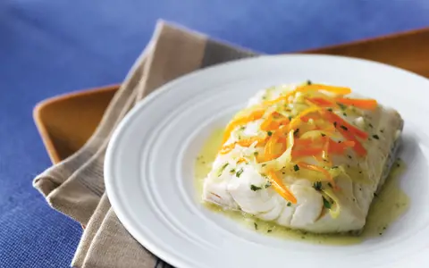 Steamed Haddock on plate with carrots and leeks 
