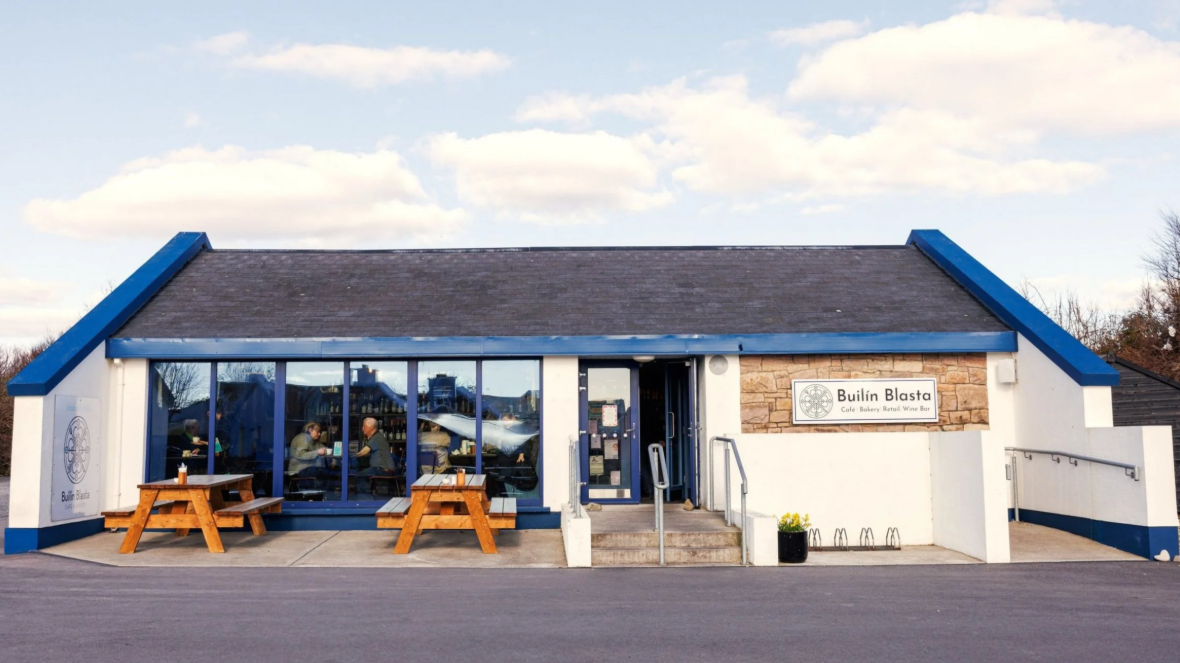 Builín Blasta premises, with benches and people sitting outside in front of the business.