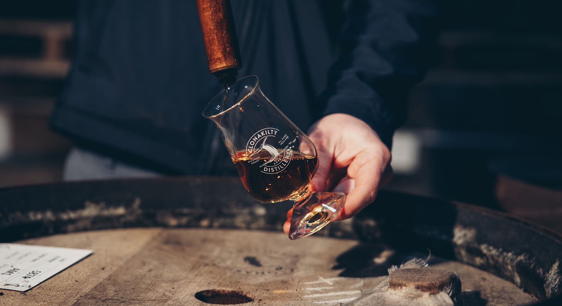 Hands pouring Clonakilty distillery product into a whiskey glass