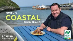 Neven sat at a picnic table beside the sea with a plate of seafood infront of him.